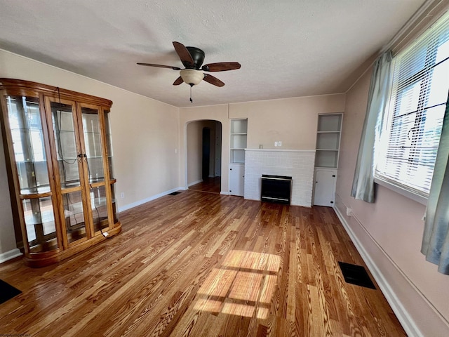 600 Wilson St, Elkins, WV 26241 - unfurnished living room with arched walkways, a fireplace, plenty of natural light, wood finished floors, and a textured ceiling