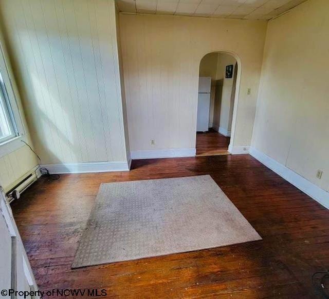 140 Locust Ave Unit 6, Fairmont, WV 26554 - empty room featuring arched walkways, a baseboard heating unit, wood finished floors, wooden walls, and baseboards