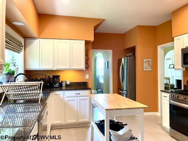 5 Key St, Elkins, WV 26241 - kitchen with appliances with stainless steel finishes, white cabinets, arched walkways, and light tile patterned floors