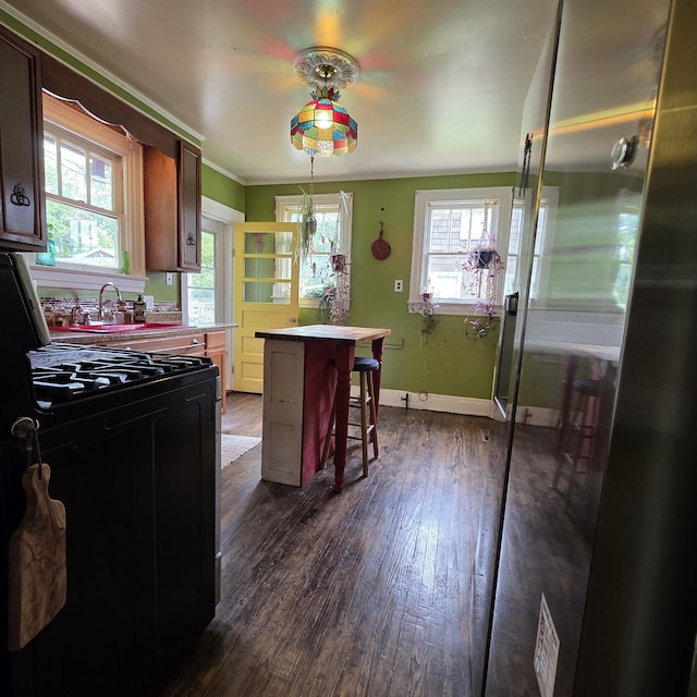 147 E 6th St, Weston, WV 26452 - kitchen with black range with gas cooktop, dark wood finished floors, a breakfast bar area, a kitchen island, and a sink