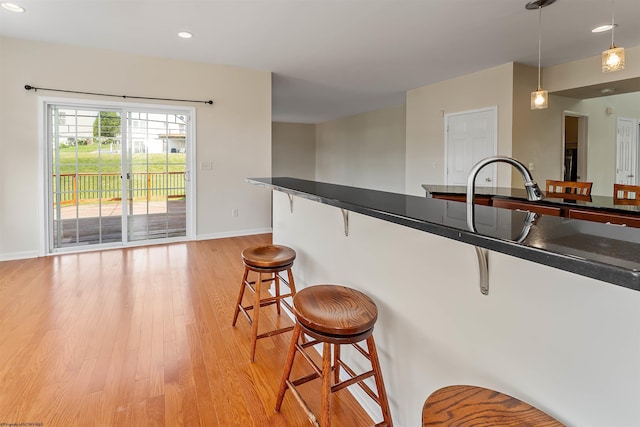 453 Blackberry Ridge Dr, Morgantown, WV 26508 - kitchen with a kitchen breakfast bar, light wood-style flooring, dark countertops, hanging light fixtures, and recessed lighting
