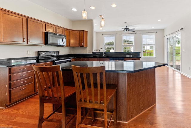453 Blackberry Ridge Dr, Morgantown, WV 26508 - kitchen featuring black appliances, dark countertops, light wood finished floors, recessed lighting, and a kitchen bar