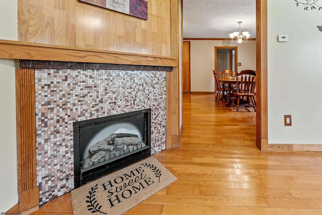 2228 Dinnerbell Five Forks Rd, Farmington, PA 15437 - detailed view of wood finished floors, a tiled fireplace, a chandelier, crown molding, and a textured ceiling