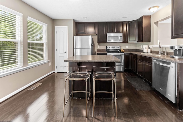 126 Auburn Dr, Morgantown, WV 26501 - kitchen with appliances with stainless steel finishes, dark brown cabinets, dark countertops, a breakfast bar, and dark wood finished floors
