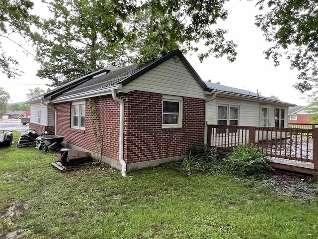 101 Wilson St, Elkins, WV 26241 - view of home's exterior featuring a wooden deck, a lawn, brick siding, and a metal roof