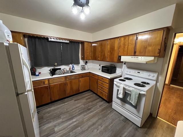 101 Wilson St, Elkins, WV 26241 - kitchen with white appliances, under cabinet range hood, brown cabinetry, and dark wood-style floors