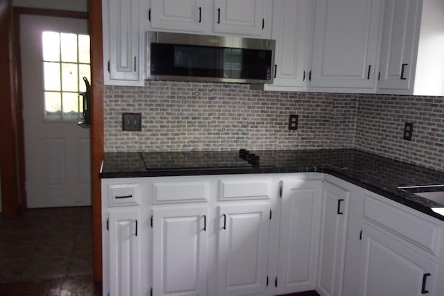 208 Parkview Cir, Kingwood, WV 26537 - kitchen with stainless steel microwave, dark countertops, white cabinetry, and decorative backsplash