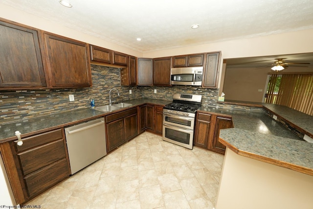 103 Apolla Dr, Morgantown, WV 26505 - kitchen featuring appliances with stainless steel finishes, decorative backsplash, dark countertops, a ceiling fan, and a peninsula
