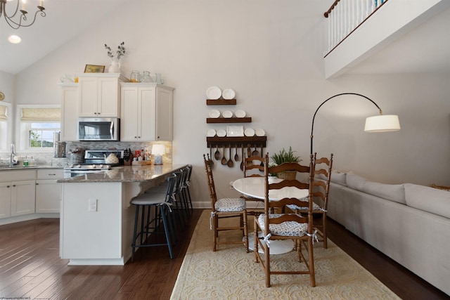 211 Berkshire Cir, Bridgeport, WV 26330 - kitchen with stainless steel appliances, high vaulted ceiling, white cabinets, a kitchen bar, and dark wood-type flooring