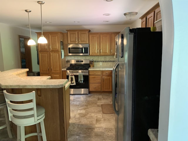 52 Ladder Dr, Mount Clare, WV 26408 - kitchen with appliances with stainless steel finishes, light countertops, a kitchen bar, stone finish floors, and pendant lighting