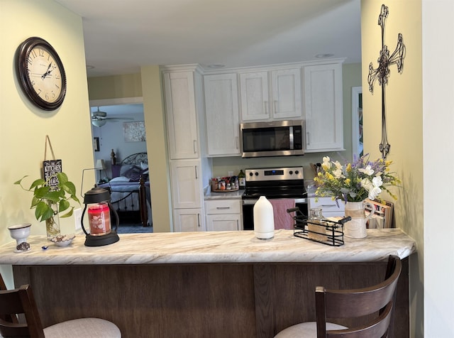 114 Snowy Ridge Rd, Terra Alta, WV 26764 - kitchen featuring appliances with stainless steel finishes, white cabinets, a kitchen bar, and a ceiling fan