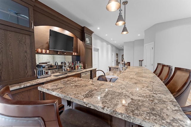 1009 Summit Dr, Morgantown, WV 26508 - kitchen with a breakfast bar, dark brown cabinetry, pendant lighting, a kitchen island with sink, and decorative backsplash