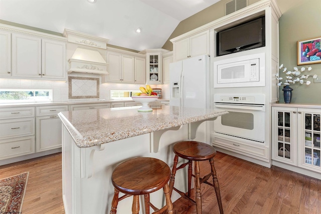 1348 Anderson Ave, Morgantown, WV 26505 - kitchen with white appliances, backsplash, vaulted ceiling, a breakfast bar, and glass insert cabinets