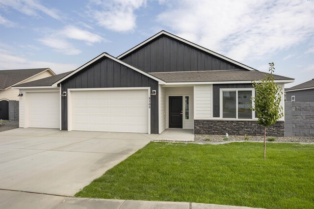 8509 Ashen Dr, Pasco, WA 99301 - craftsman house with a garage, driveway, a shingled roof, a front lawn, and stone siding