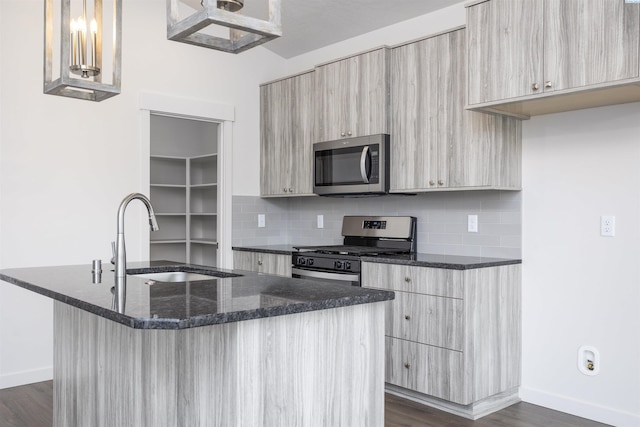 8509 Ashen Dr, Pasco, WA 99301 - kitchen featuring appliances with stainless steel finishes, modern cabinets, a kitchen island with sink, dark stone countertops, and tasteful backsplash