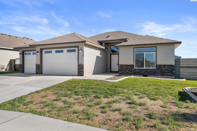 prairie-style home with concrete driveway, an attached garage, stone siding, and a front lawn