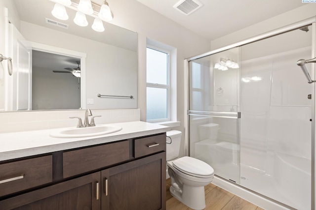 bathroom featuring ceiling fan, hardwood / wood-style floors, vanity, a shower with shower door, and toilet