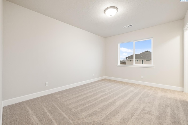 spare room featuring carpet floors and a textured ceiling