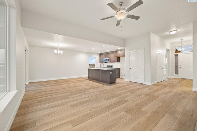 unfurnished living room featuring sink, ceiling fan with notable chandelier, and light wood-type flooring