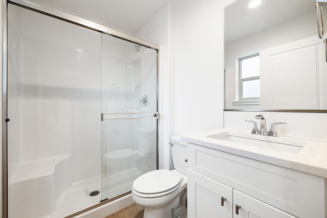 full bathroom featuring toilet, a shower stall, wood finished floors, and vanity