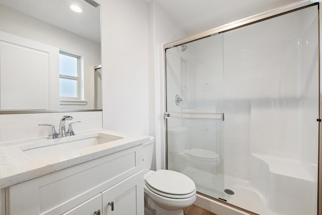 full bath with vanity, decorative backsplash, a stall shower, and toilet