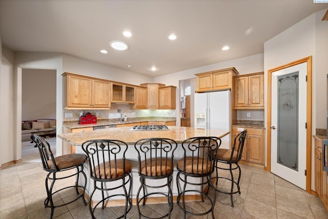 3610 S Johnson St, Kennewick, WA 99337 - kitchen featuring stainless steel appliances, a kitchen island, light stone countertops, a kitchen bar, and tasteful backsplash