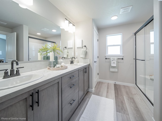 full bath with visible vents, a sink, a shower stall, and wood finished floors