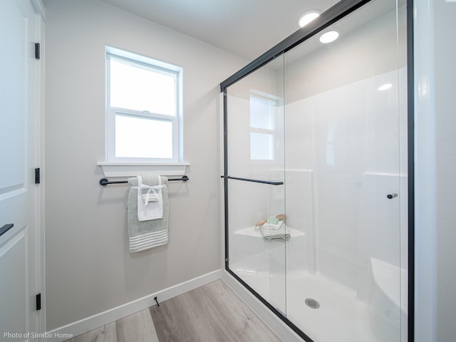 full bath with a shower stall, baseboards, and wood finished floors