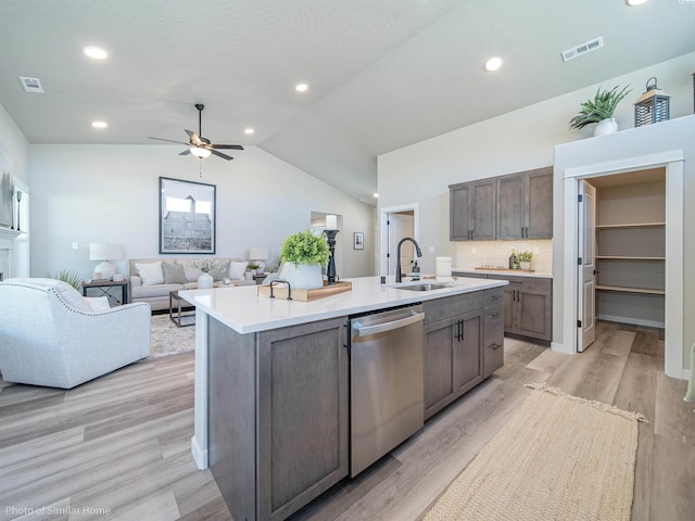 kitchen with a center island with sink, visible vents, light countertops, stainless steel dishwasher, and a sink