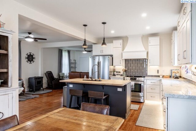 501 W California St, Garfield, WA 99130 - kitchen featuring custom range hood, ceiling fan, appliances with stainless steel finishes, a wood stove, and open floor plan