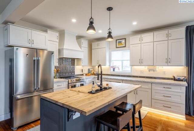 501 W California St, Garfield, WA 99130 - kitchen with stainless steel appliances, butcher block counters, custom range hood, a kitchen breakfast bar, and white cabinets