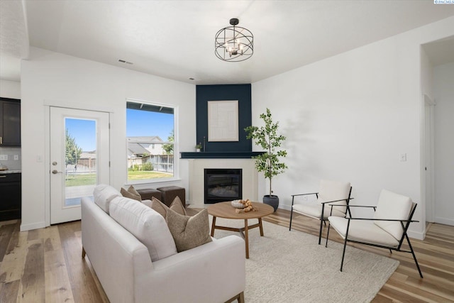 882 Pikes Peak Dr, West Richland, WA 99353 - living area with a glass covered fireplace, light wood-type flooring, a chandelier, and baseboards
