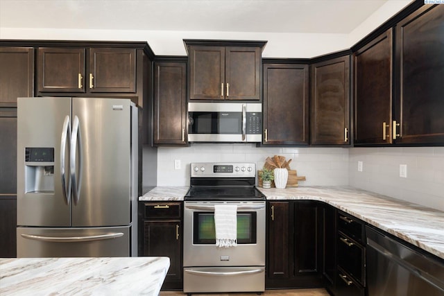 882 Pikes Peak Dr, West Richland, WA 99353 - kitchen featuring stainless steel appliances, light stone countertops, dark brown cabinets, and backsplash