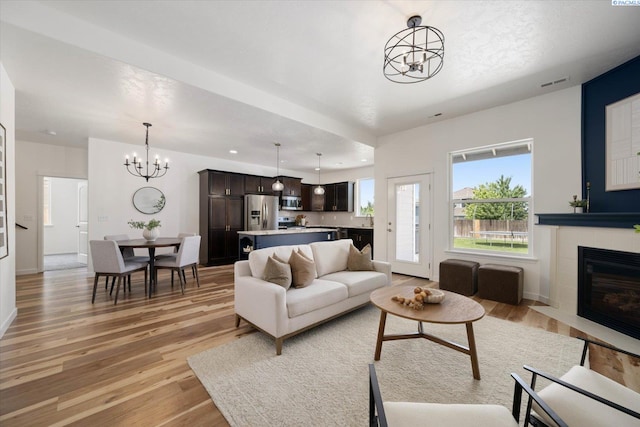 882 Pikes Peak Dr, West Richland, WA 99353 - living area with a chandelier, light wood finished floors, a fireplace, and baseboards
