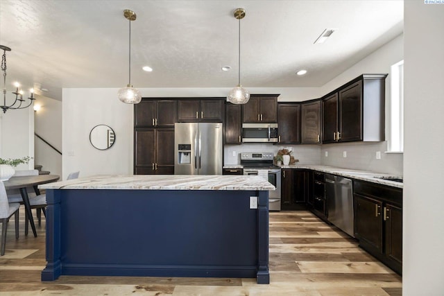 882 Pikes Peak Dr, West Richland, WA 99353 - kitchen featuring appliances with stainless steel finishes, dark brown cabinets, a center island, tasteful backsplash, and light wood-style floors