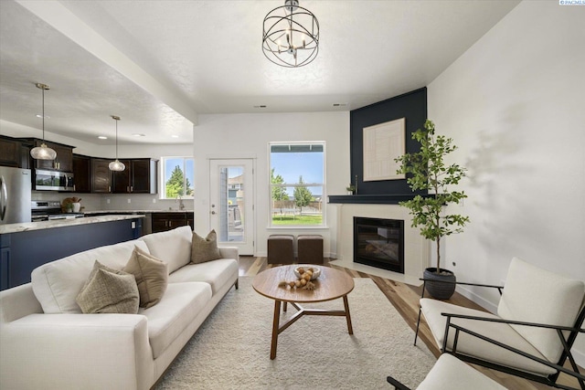 882 Pikes Peak Dr, West Richland, WA 99353 - living area with light wood-style floors, a fireplace with flush hearth, baseboards, and a chandelier