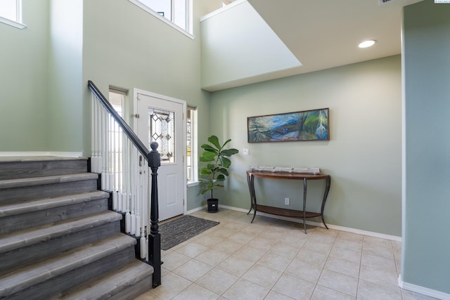 entryway with light tile patterned floors, recessed lighting, a towering ceiling, stairway, and baseboards