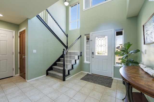 entrance foyer featuring a healthy amount of sunlight, stairway, baseboards, and light tile patterned floors