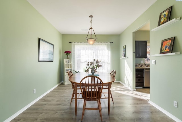 dining room with light wood-type flooring, visible vents, and baseboards