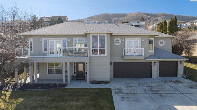 view of front facade featuring a balcony, driveway, and french doors