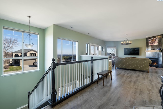 corridor featuring an upstairs landing, wood finished floors, visible vents, and baseboards