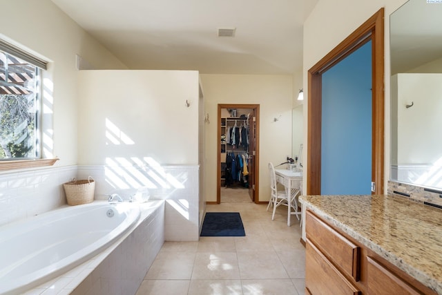 bathroom featuring visible vents, a spacious closet, vanity, tile patterned flooring, and a bath