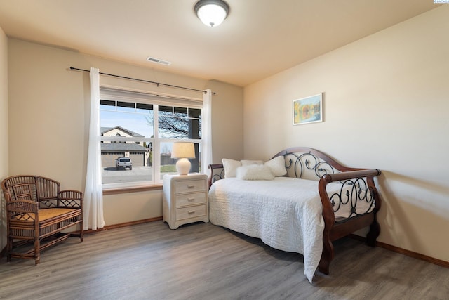 bedroom featuring visible vents, baseboards, and wood finished floors