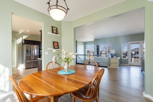 dining area with light wood-style floors, a notable chandelier, and baseboards