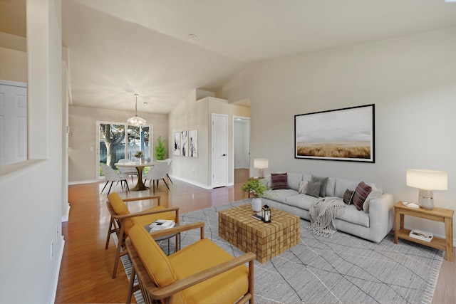 living room with wood-type flooring, vaulted ceiling, and a notable chandelier