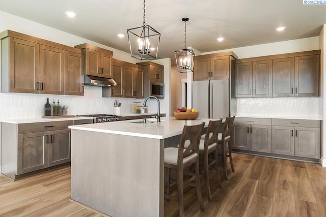 12110 Dunsmuir Dr, Pasco, WA 99301 - kitchen featuring under cabinet range hood, stainless steel microwave, tasteful backsplash, a chandelier, and recessed lighting