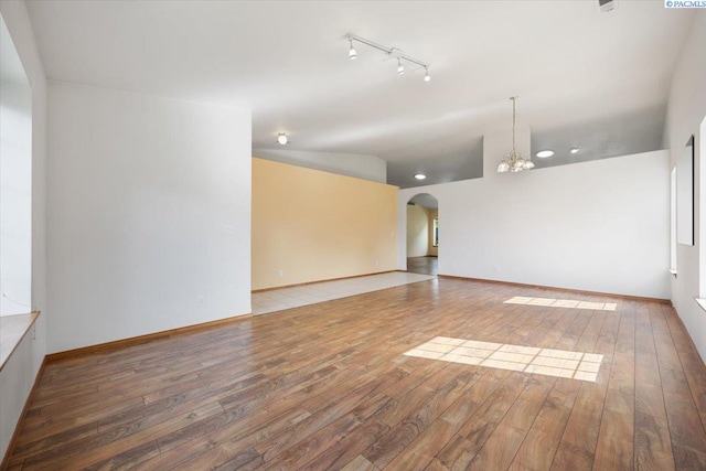 3438 S Buntin Ct, Kennewick, WA 99337 - unfurnished room with wood-type flooring, a chandelier, vaulted ceiling, arched walkways, and rail lighting