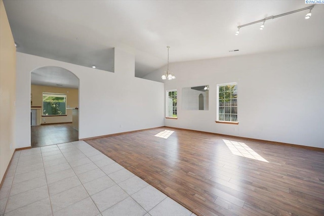 3438 S Buntin Ct, Kennewick, WA 99337 - spare room featuring a chandelier, wood finished floors, rail lighting, vaulted ceiling, and arched walkways