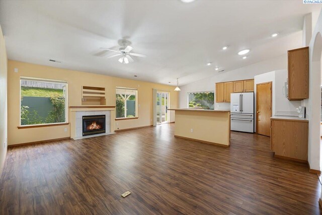 3438 S Buntin Ct, Kennewick, WA 99337 - unfurnished living room with ceiling fan, dark wood-type flooring, vaulted ceiling, a tile fireplace, and baseboards