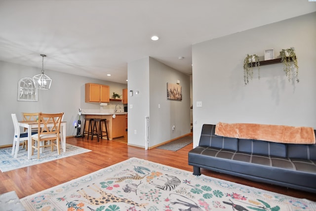 living room with an inviting chandelier, sink, and light wood-type flooring